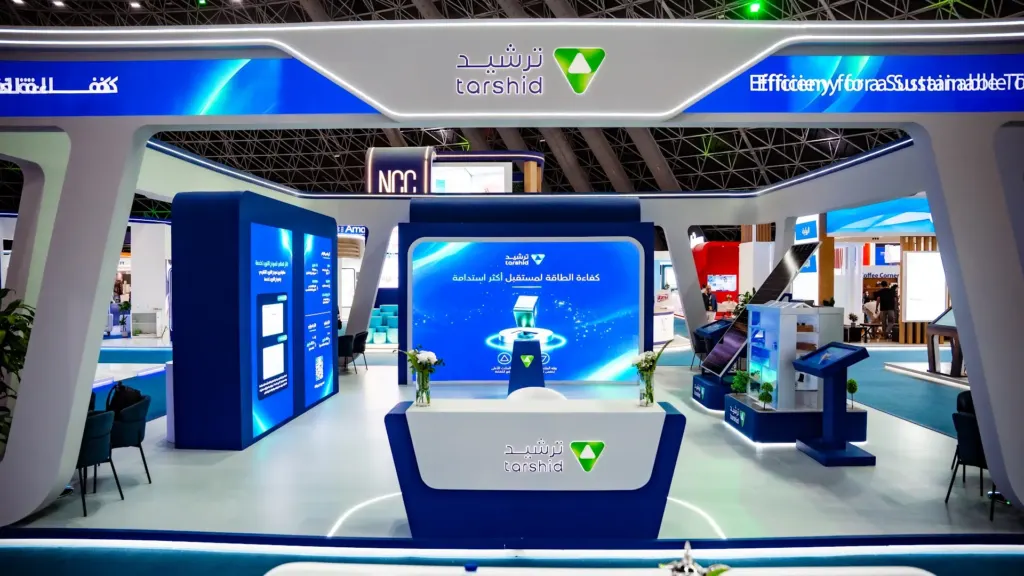 View into the Tarshid booth: reception counter, curved LED wall and touchscreen kiosks