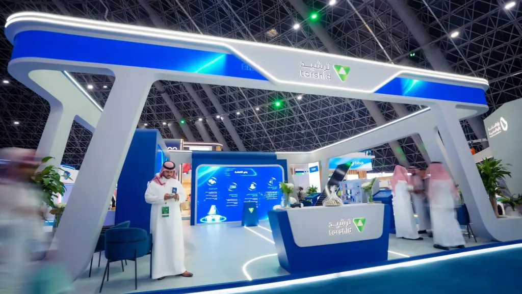 Front of the Tarshid stand with the branded reception counter and LED screens behind it